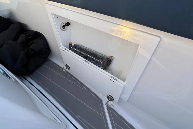 Slide: The Image of 2026 Monterey Elite 30 OB boat storage compartment with hose and black bag. - 29