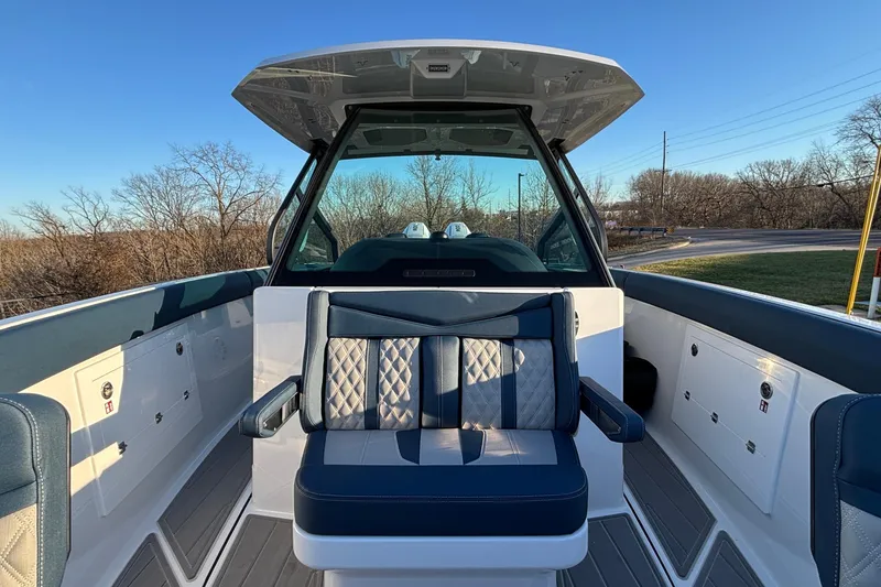 Slide: The Image of 2026 Monterey Elite 30 OB boat interior with blue and white seating, under clear sky. - 31