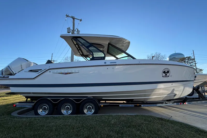 Slide: The Image of 2026 Monterey Elite 30 OB boat on trailer, side view, clear sky background. - 44