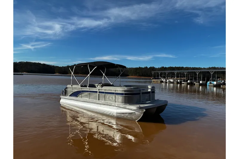 The Image of 2023 Bennington 22 SSR pontoon boat on a calm lake under a clear blue sky. - 0