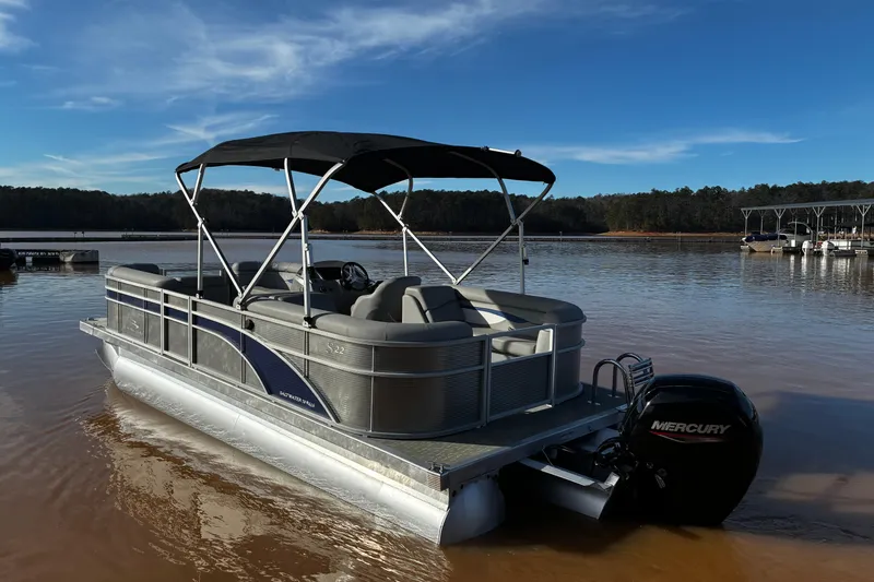 Slide: The Image of 2023 Bennington 22 SSR pontoon boat on a calm lake with clear skies. - 3
