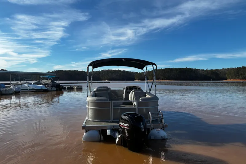 Slide: The Image of 2023 Bennington 22 SSR pontoon boat on a calm lake under a clear blue sky. - 4