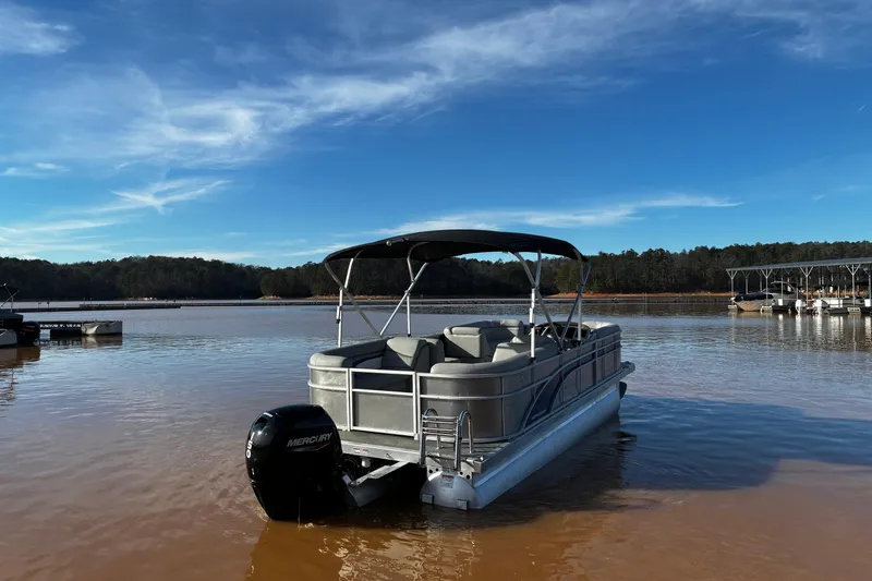 Slide: The Image of 2023 Bennington 22 SSR pontoon boat on a calm lake under a clear blue sky. - 5