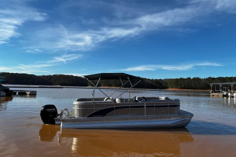 Slide: The Image of 2023 Bennington 22 SSR pontoon boat on calm lake under clear blue sky. - 6