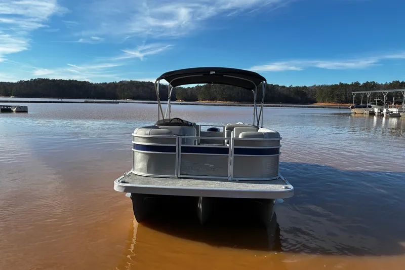 Slide: The Image of 2023 Bennington 22 SSR pontoon boat on a calm lake under a clear blue sky. - 7
