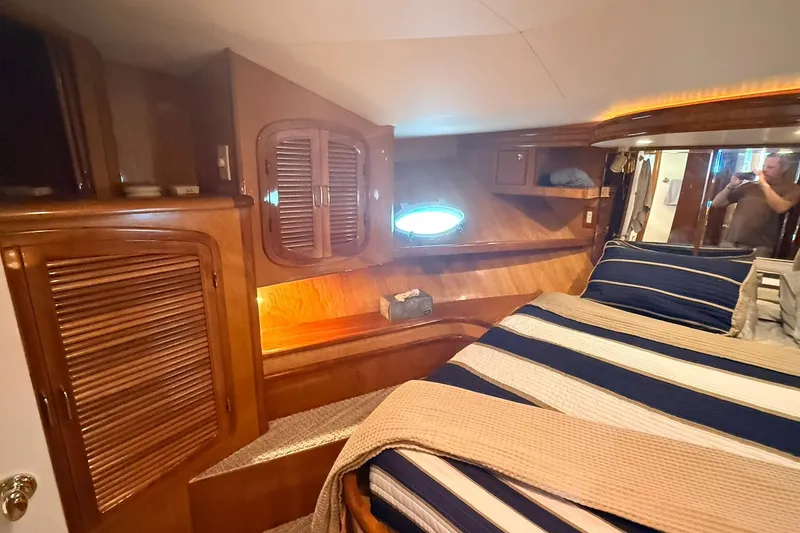 Slide: The Image of Luxurious cabin interior of a 2003 Mikelson 50 yacht with wood paneling and striped bedding. - 11