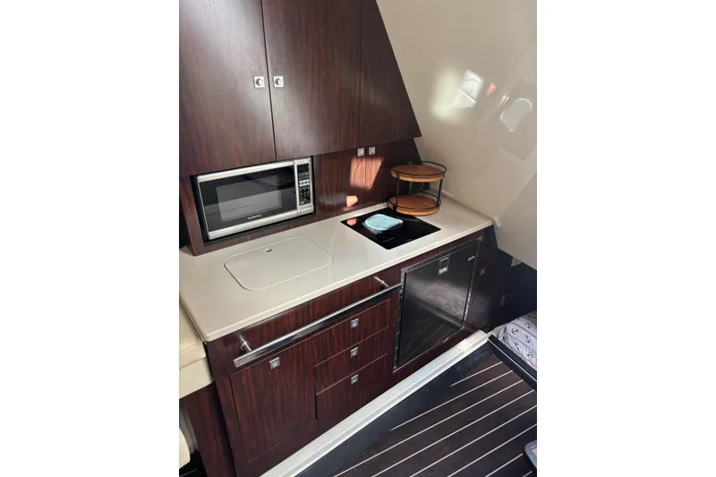 Slide: The Image of 2015 Monterey 360 Sport Coupe kitchen with microwave, stove, and wooden cabinetry. - 18