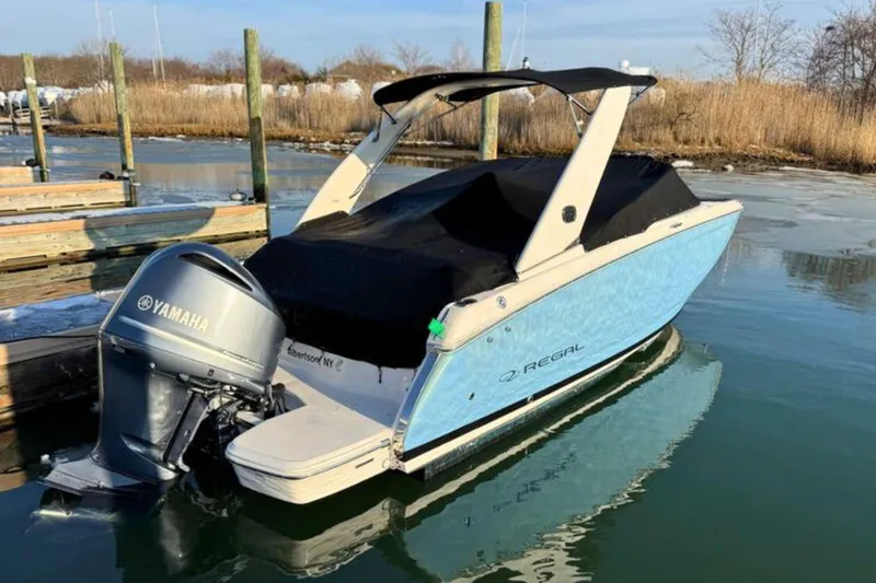 Slide: The Image of 2019 Regal 23 OBX boat with Yamaha outboard motor docked on calm water. - 2