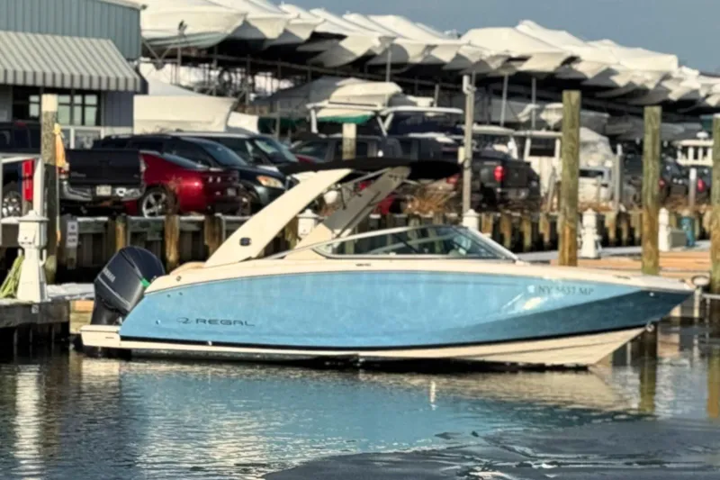 Slide: The Image of 2019 Regal 23 OBX boat docked at marina with covered boats in background. - 3