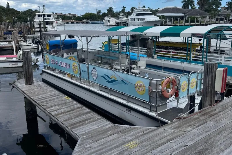Slide: The Image of 2020 A&M Manufacturing 32 Pontoon boat docked at marina, featuring colorful signage. - 2