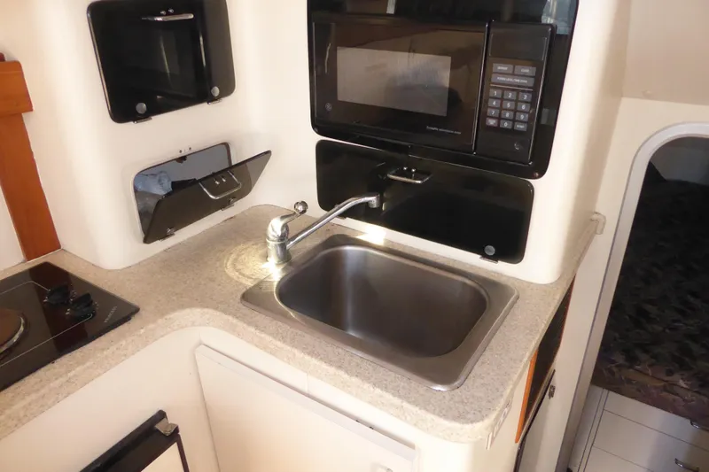 Slide: The Image of Compact kitchen area in a 1996 Luhrs 320 Tournament boat, featuring a sink and microwave. - 12