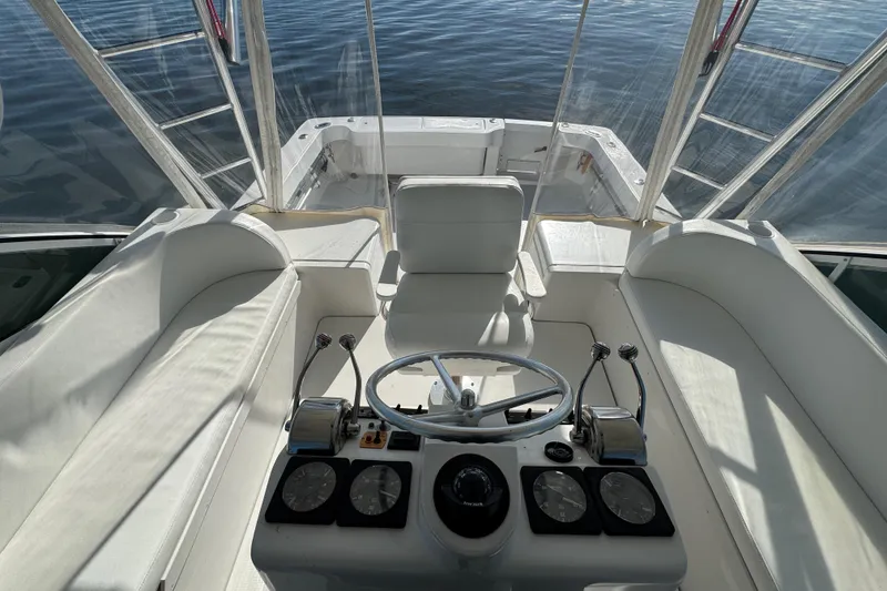Slide: The Image of 2002 Luhrs 32 Open boat helm with steering wheel and controls, overlooking calm water. - 14