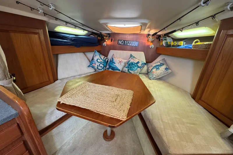 Slide: The Image of 2002 Luhrs 32 Open cabin interior with cozy seating and nautical-themed pillows. - 18