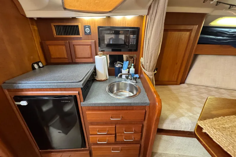 Slide: The Image of 2002 Luhrs 32 Open yacht interior with kitchenette, featuring sink, microwave, and mini fridge. - 19