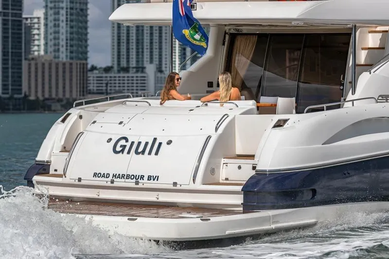 Slide: The Image of Sunseeker Manhattan 74 yacht cruising with two people onboard, city skyline in background. - 12