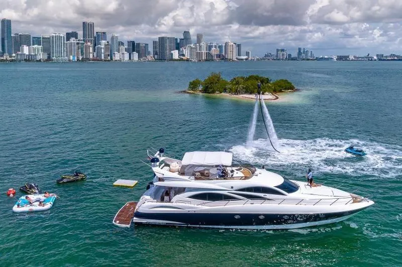 Slide: The Image of Sunseeker Manhattan 74 yacht near island, with water activities and city skyline in background. - 42