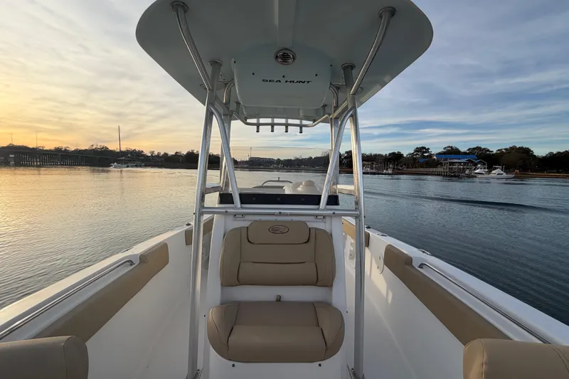 Slide: The Image of 2014 Sea Hunt Ultra 225 boat on calm water at sunset, featuring comfortable seating. - 29