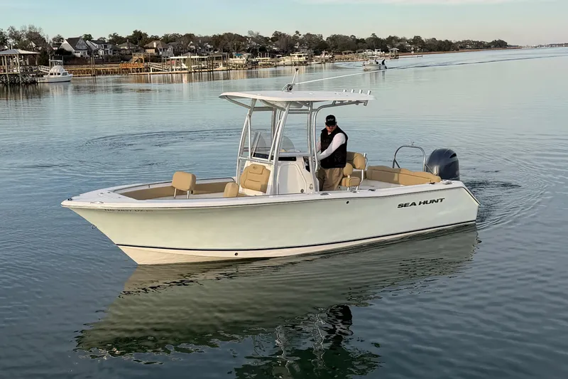 Slide: The Image of 2014 Sea Hunt Ultra 225 boat cruising on calm water, with a person at the helm. - 3