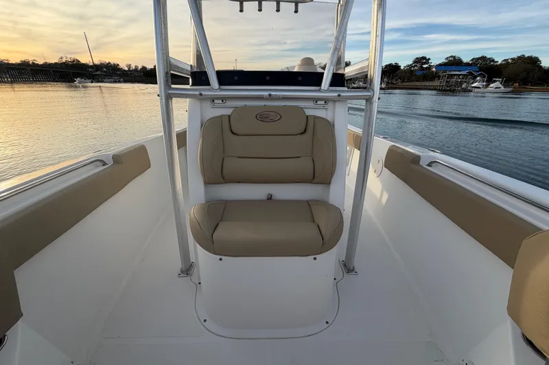 Slide: The Image of 2014 Sea Hunt Ultra 225 boat interior with beige seating, calm water backdrop. - 30