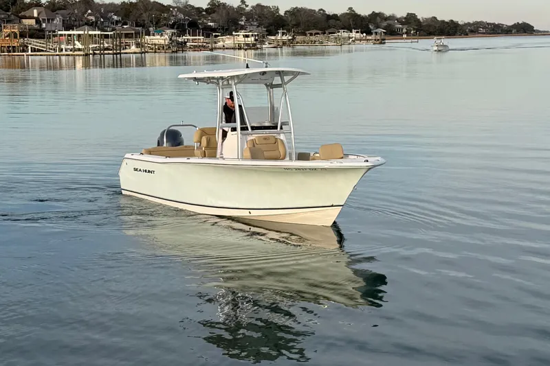 Slide: The Image of 2014 Sea Hunt Ultra 225 boat cruising on calm waters near a coastal town. - 4