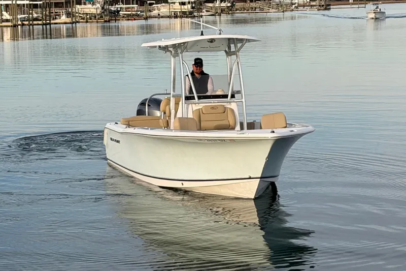 Slide: The Image of 2014 Sea Hunt Ultra 225 boat cruising on calm water with a person at the helm. - 5
