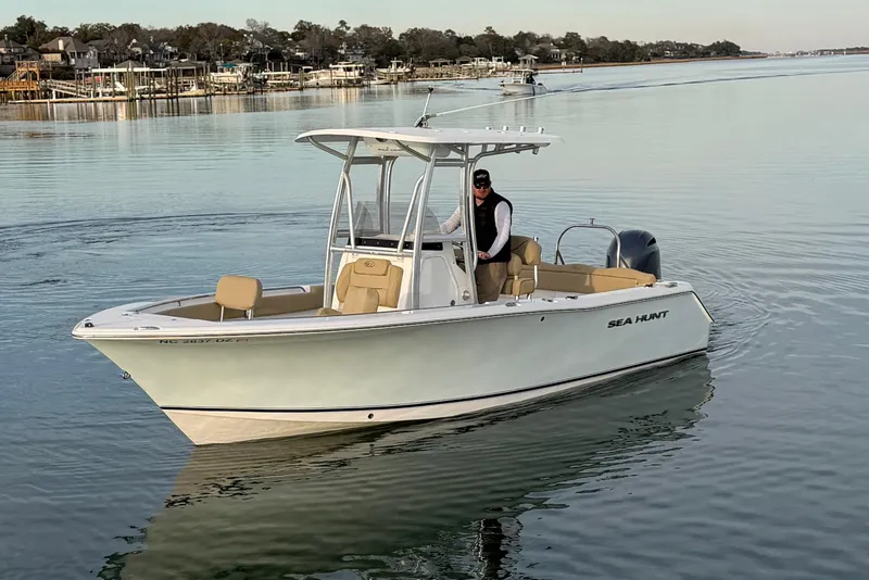 Slide: The Image of 2014 Sea Hunt Ultra 225 boat cruising on calm water with scenic background. - 7