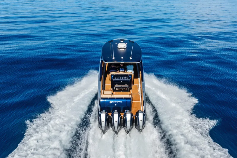 Slide: The Image of 2021 Mystic Powerboats M4200 cruising on open blue water, rear view. - 10