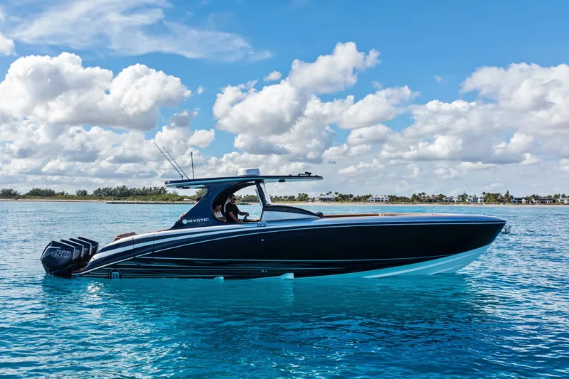 Slide: The Image of 2021 Mystic Powerboats M4200 cruising on clear blue water under a partly cloudy sky. - 3