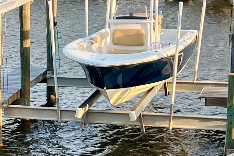 Slide: The Image of 2021 Sportsman Heritage 211 Center Console boat on a lift over water. - 1