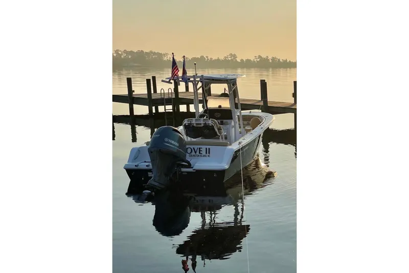 Slide: The Image of 2021 Sportsman Heritage 211 Center Console boat docked at sunrise, calm water reflection. - 2
