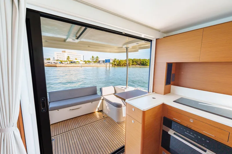Slide: The Image of 2025 Beneteau Swift Trawler 41 Fly with spacious deck seating, cruising near a coastal area. - 17