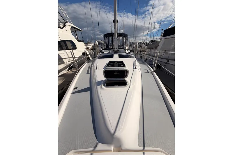 Slide: The Image of 2004 Hunter Passage 420 sailboat docked, showcasing sleek deck design under a partly cloudy sky. - 21