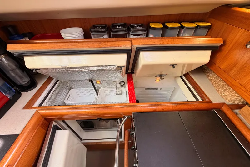 Slide: The Image of 2004 Hunter Passage 420 yacht kitchen with open storage compartments and organized containers. - 49