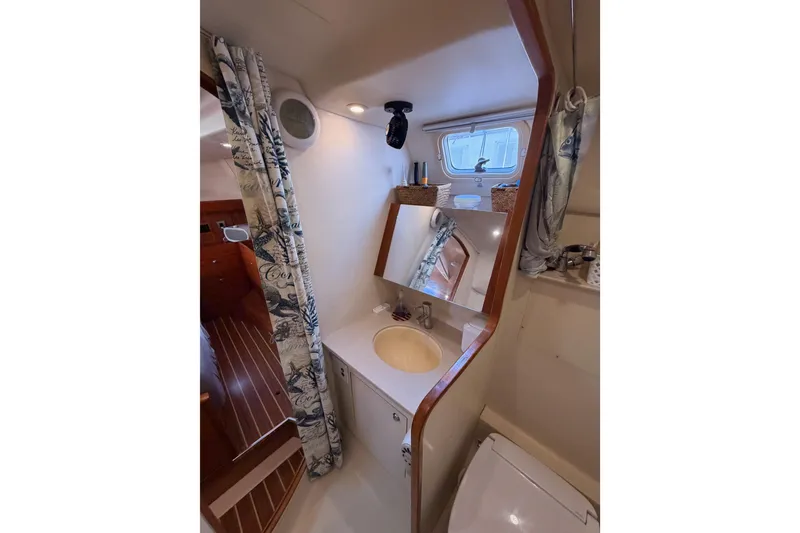 Slide: The Image of Bathroom interior of 2004 Hunter Passage 420 sailboat, featuring sink, mirror, and nautical decor. - 71