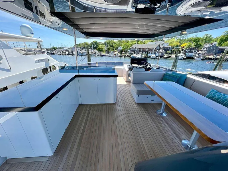 Slide: The Image of Modern 2023 Sirena 68 yacht deck with seating, dining area, and waterfront view. - 14