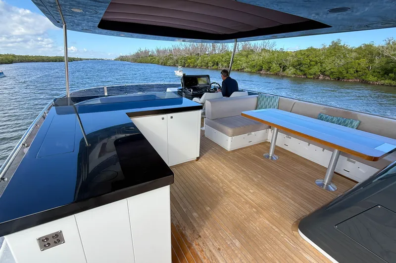 Slide: The Image of Luxurious 2023 Sirena 68 yacht deck with seating, table, and helm, cruising on a scenic river. - 15