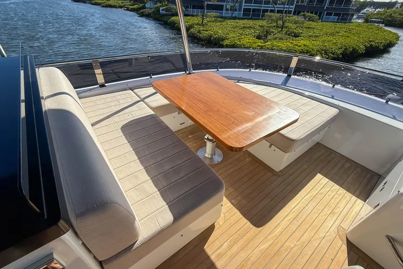 Slide: The Image of Outdoor seating area on 2023 Sirena 68 yacht with wooden table and cushioned benches. - 21