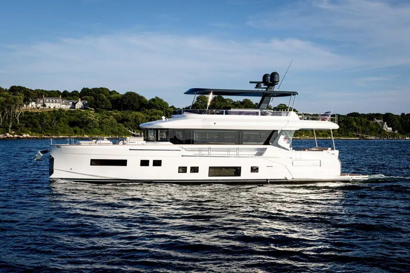 Slide: The Image of 2023 Sirena 68 yacht cruising on a serene lake with lush green shoreline. - 3