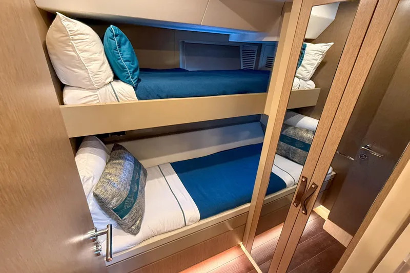 Slide: The Image of Bunk beds in 2023 Sirena 68 yacht cabin with blue bedding and wooden finishes. - 56