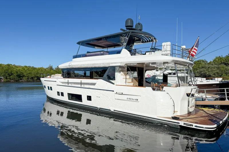 Slide: The Image of 2023 Sirena 68 yacht docked on calm water under clear blue sky. - 7