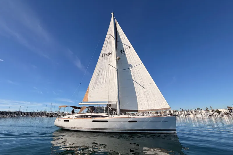 The Image of 2011 Jeanneau 53 sailboat on calm water under clear blue sky. - 0
