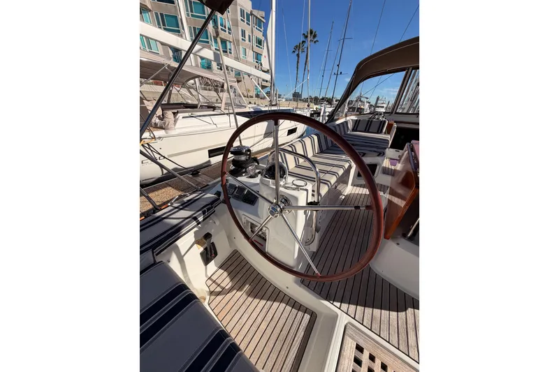 Slide: The Image of 2011 Jeanneau 53 yacht cockpit with striped seating and wooden steering wheel. - 22