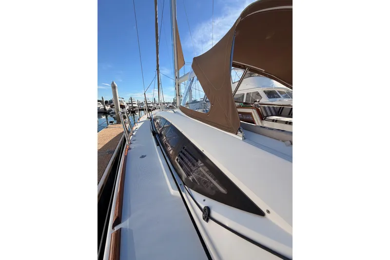 Slide: The Image of 2011 Jeanneau 53 sailboat docked, showcasing sleek deck design and canopy under clear blue sky. - 28