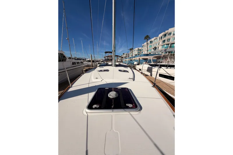 Slide: The Image of 2011 Jeanneau 53 sailboat deck view in marina, clear sky, modern buildings in background. - 35