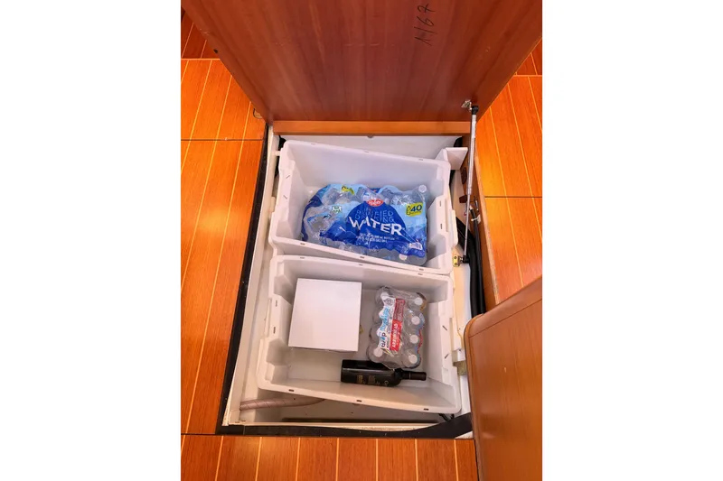 Slide: The Image of Storage compartment on 2011 Jeanneau 53 yacht with bottled water and drinks. - 87