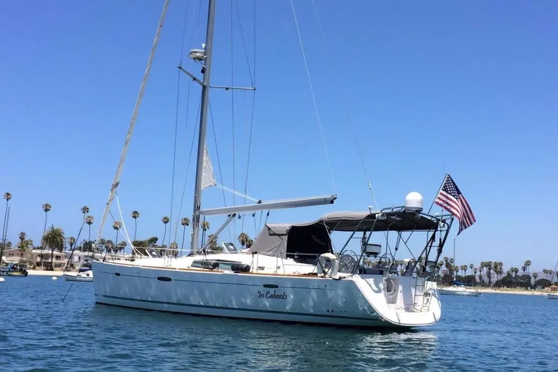 The Image of 2007 Beneteau 49 sailboat on water, American flag, clear blue sky, palm trees in background. - 1