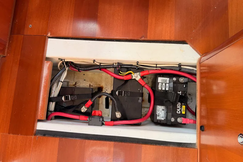 Slide: The Image of Battery compartment of a 2007 Beneteau 49 sailboat with red cables and wooden flooring. - 102