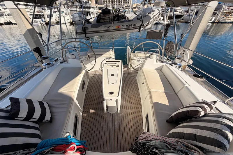 Slide: The Image of 2007 Beneteau 49 yacht cockpit with seating, striped cushions, and marina view. - 28