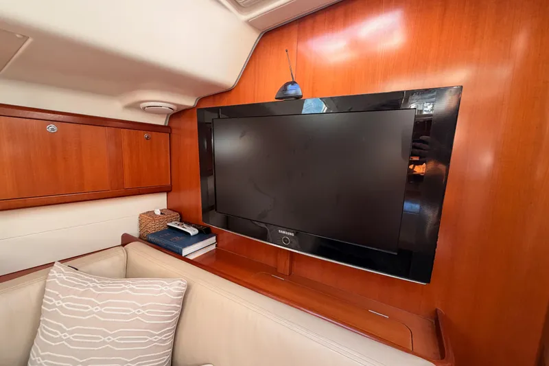 Slide: The Image of Interior of 2007 Beneteau 49 yacht with TV, wooden paneling, and cozy seating area. - 82