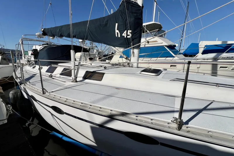 Slide: The Image of 1986 Hunter Legend 45 sailboat docked at marina, featuring sleek design and blue sail cover. - 7